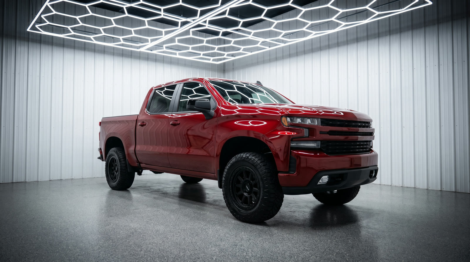 Red pickup truck with mirror-gloss paint reflecting hexagon shop lights after a full exterior detail